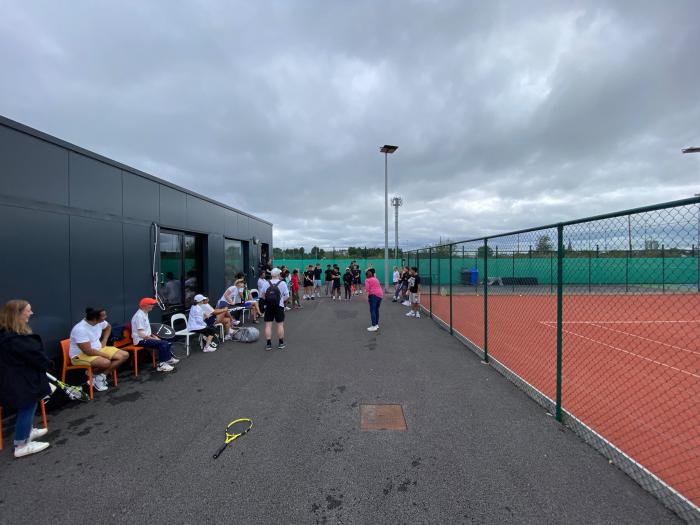 Adults in white and juniors in black gathered courtside during the Adults vs Juniors 2026 event